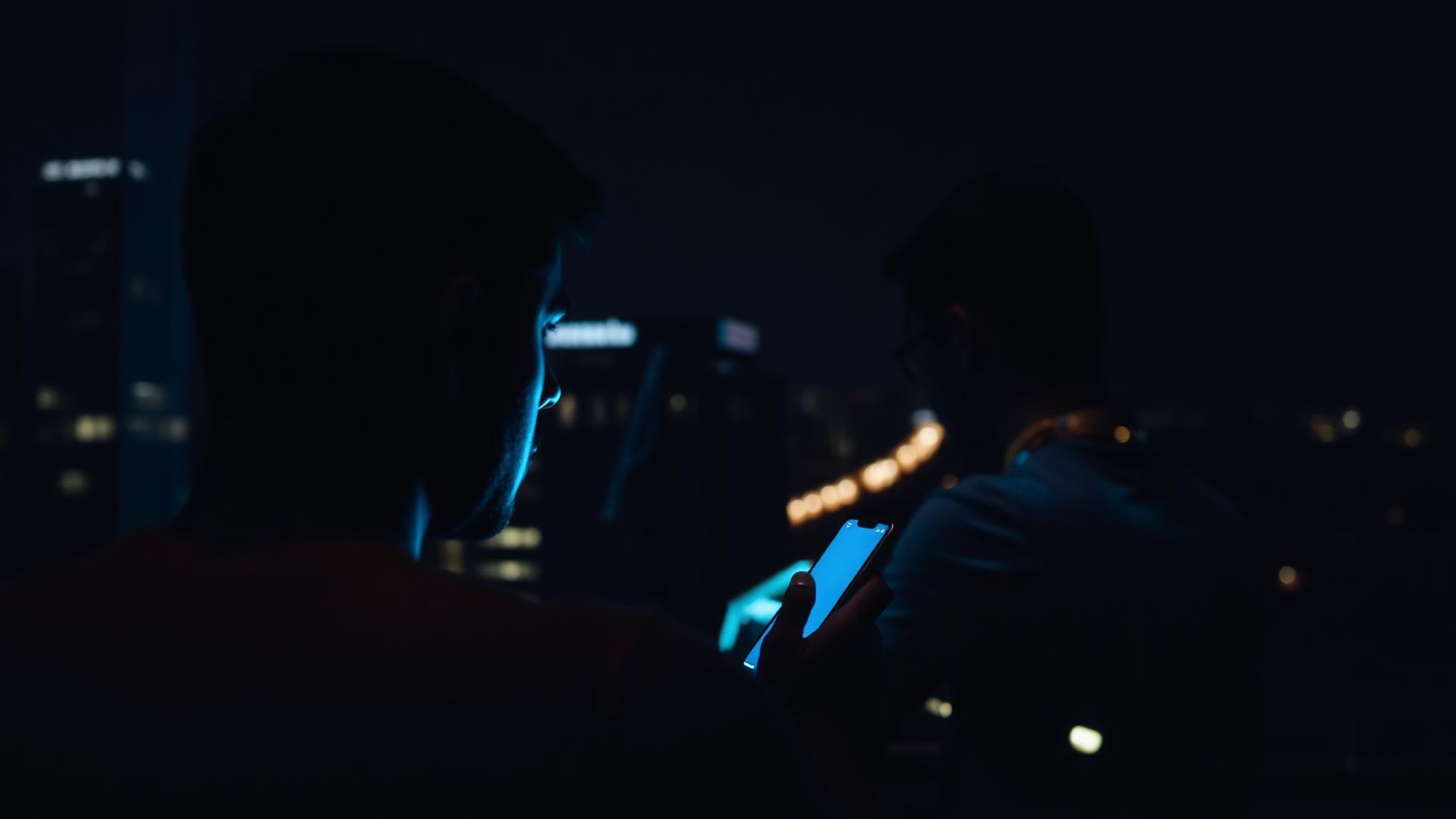 Cliente enviando mensagem pelo celular durante a madrugada